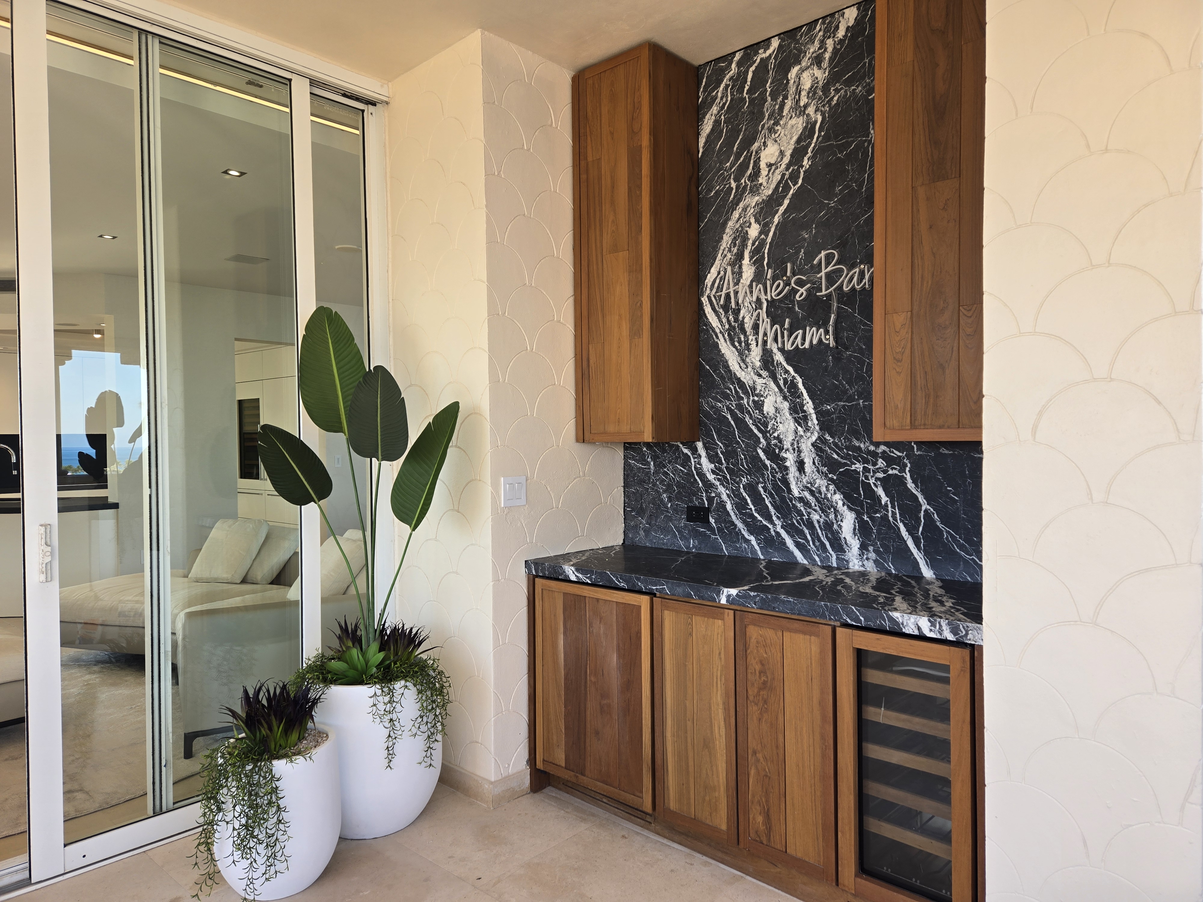 Custom outdoor bar with walnut cabinets and dark marble backsplash