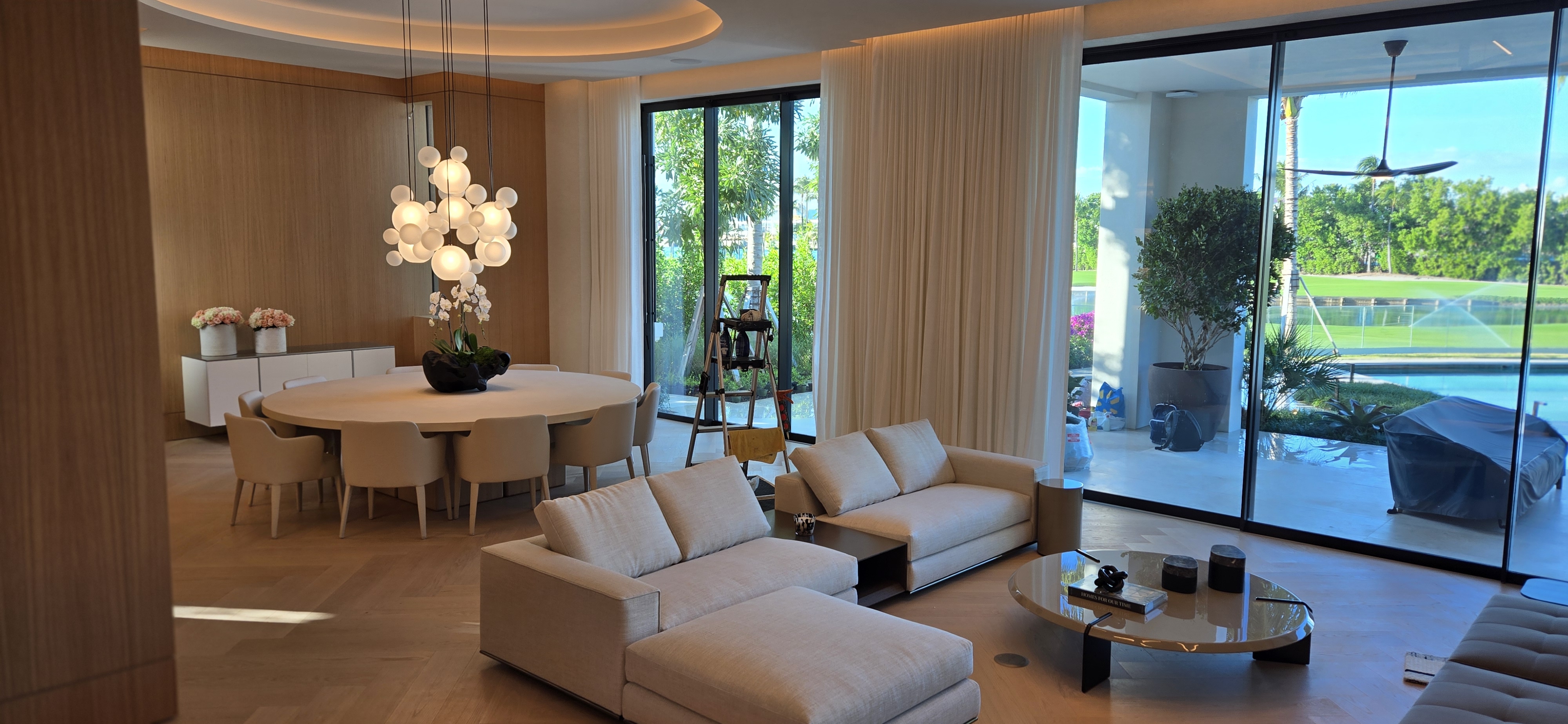 Luxury open-plan living with wood panel walls and herringbone floors
